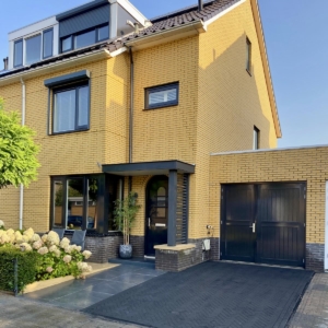 aanzicht van het huis met moderne luifel en visgraat bestrate oprit